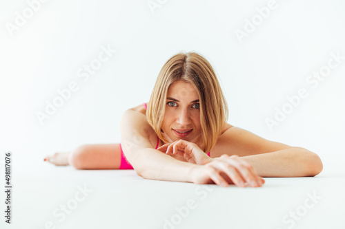 Portrait of a beautiful woman lying in sportswear during a workout on a white background  looking at the camera and smiling.