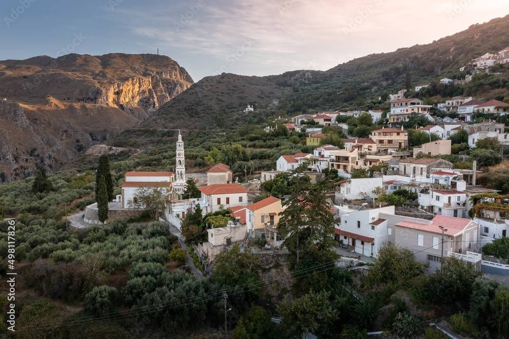 Greek village with white houses on hill slope and mountain gorge in the background, Crete, Greece