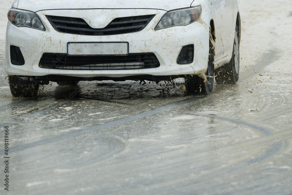 Naklejka premium car closeup on a slippery wet road during inclement weather concept bad road conditions and road safety