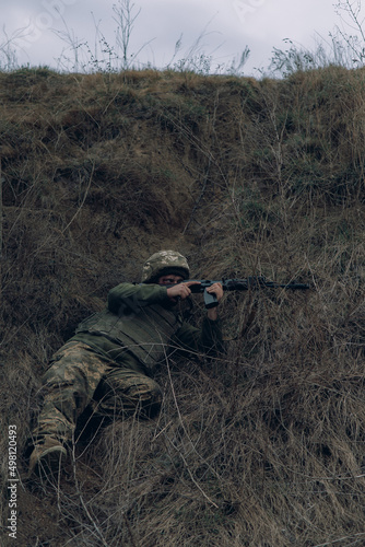 Ukrainian soldier aims from kalashnikov assault rifle to russian enemy.