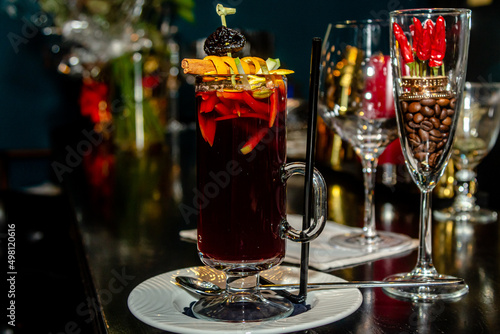 Red mulled wine in a tall glass is on the bar