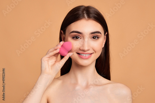 young woman posing with pink cosmetic sponges