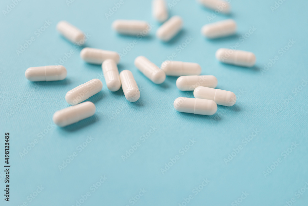 White capsule pills on a blue background. Medical background with copy space for text.
