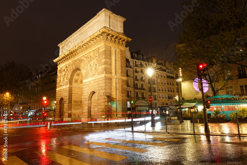 Fototapeta Naklejka Na Ścianę i Meble -  Paris, the porte Saint-Martin, beautiful ancient gate near the Grands Boulevards at rainy night.
