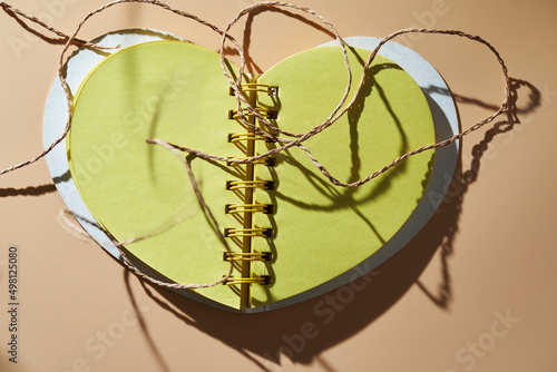 Messy tangled linen string on blank heart shaped note pad. photo