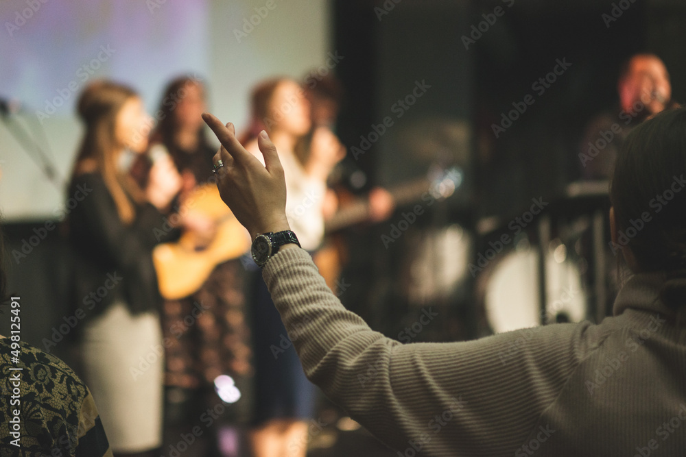 Hands in the air of a woman who praise God at church service - obrazy, fototapety, plakaty 