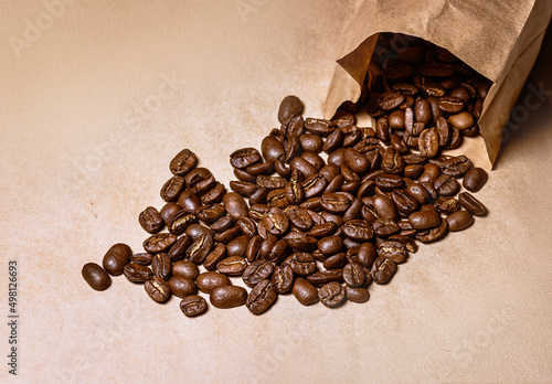 package with coffee beans lying on kraft paper and beans scattered nearby