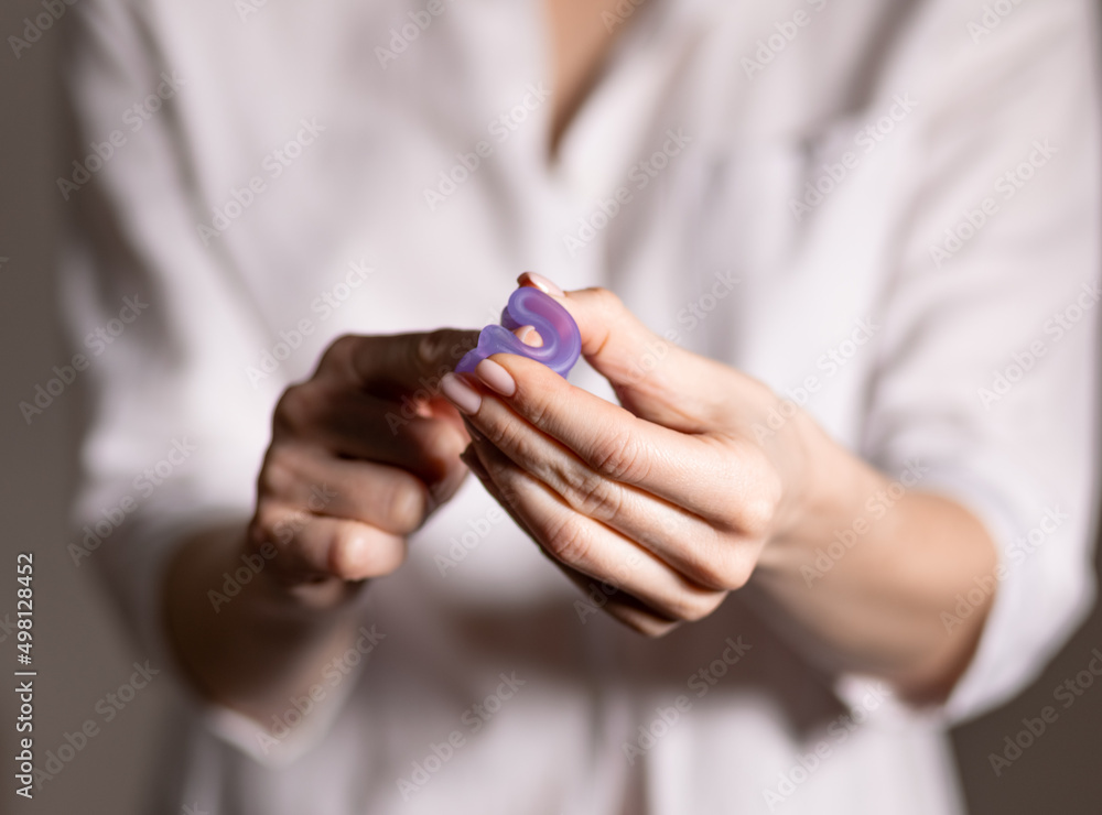 Young woman hand holding menstrual cup. Selective focus and shallow DOF