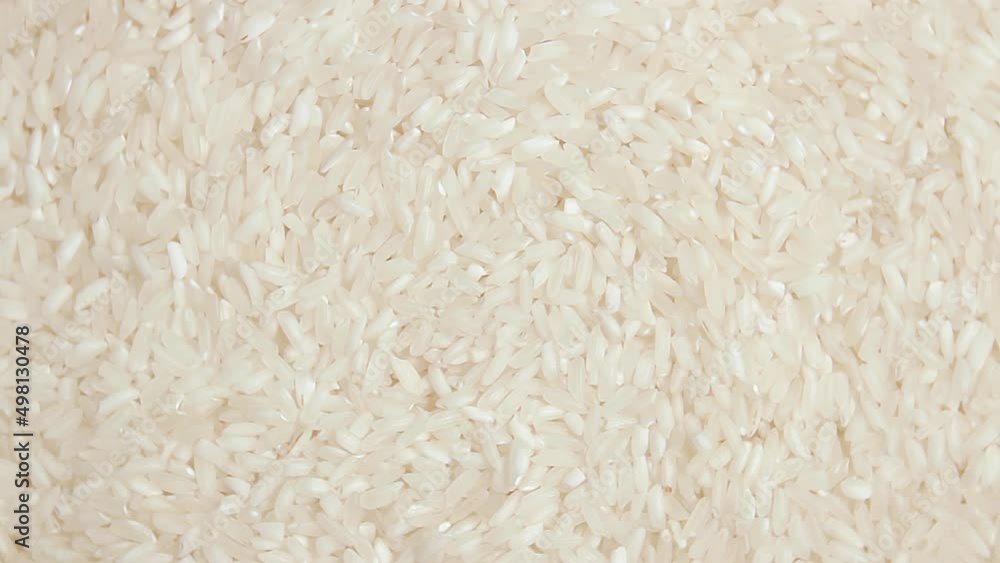 Dry Uncooked White Rice Background Slowly Rotating Right - Top View. Scattered Raw Long Grain Rice. Asian Cuisine and Culture. Healthy Eating Ingredients. Diet Food Dry Uncooked White Rice Background Slowly Rotating Right - Top View. Scattered Raw Long Grain Rice. Asian Cuisine and Culture. Healthy Eating Ingredients. Diet Food