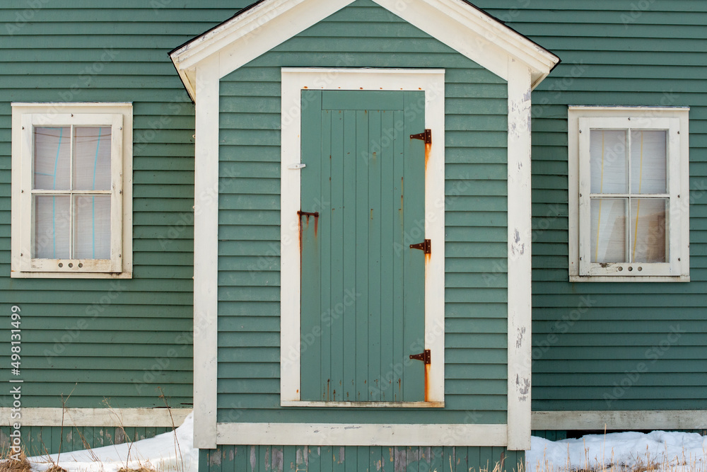 The exterior facade of a vintage wooden building. There’s a green