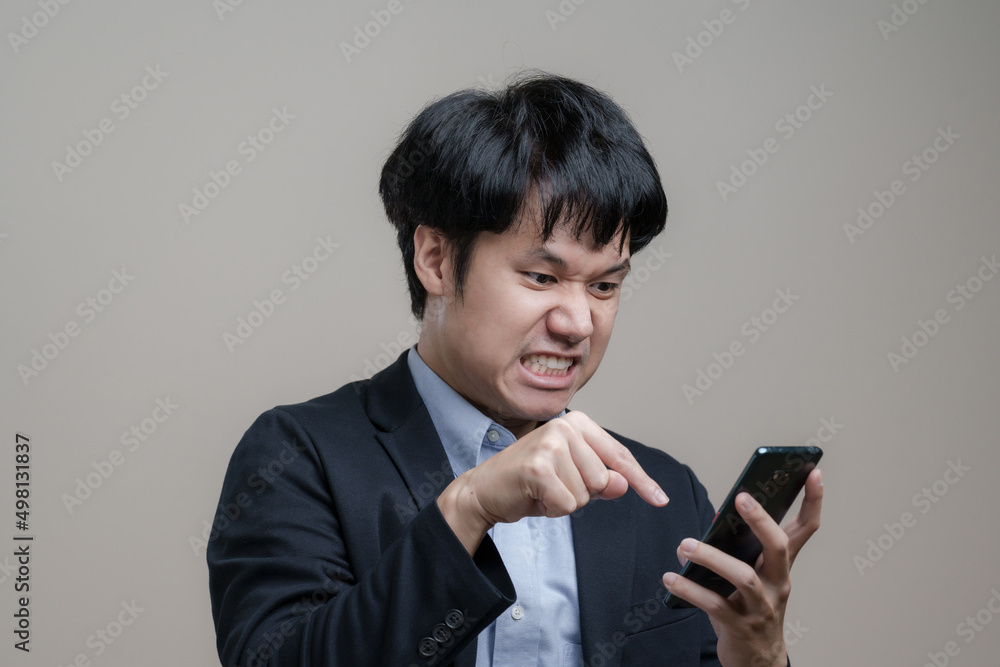 Young troubled Asian Business man Angry and get mad on the smartphone in Concept stocks and cryptocurrency fall Young troubled Asian Business man Angry and get mad on the smartphone in Concept stocks and cryptocurrency fall
