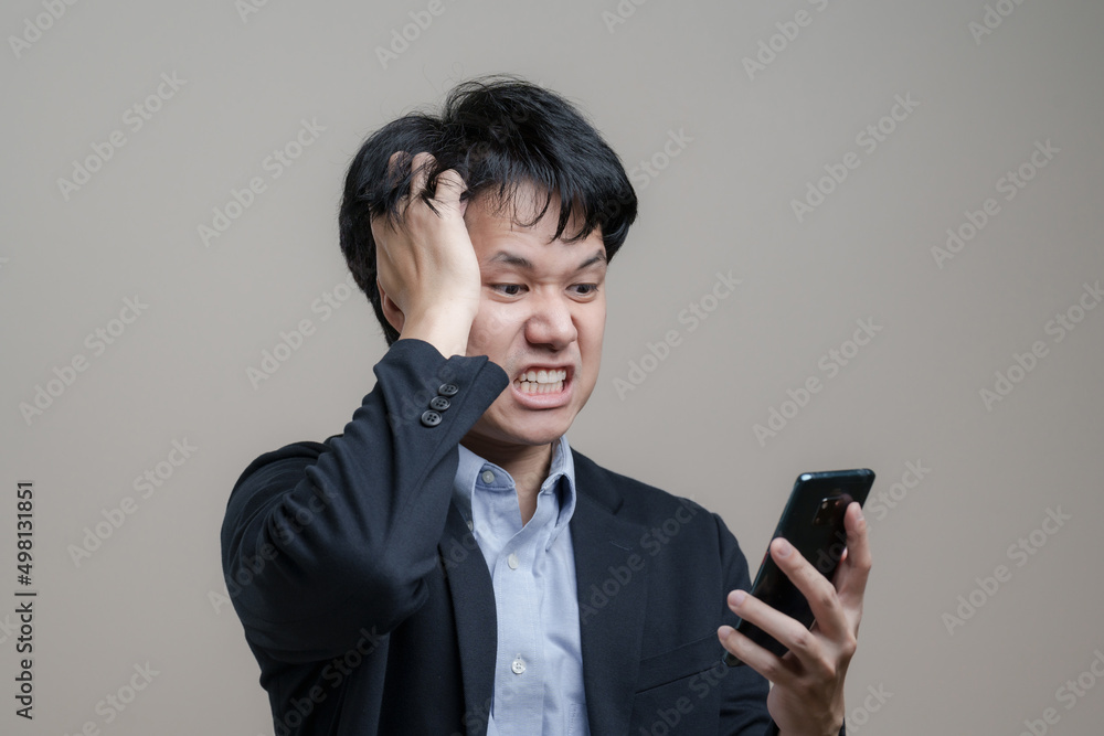 Young troubled Asian Business man Angry and get mad on the smartphone in Concept stocks and cryptocurrency fall Young troubled Asian Business man Angry and get mad on the smartphone in Concept stocks and cryptocurrency fall