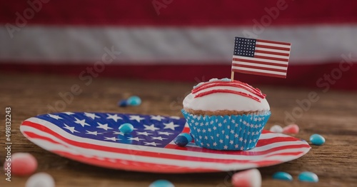 Miniature american flag over a cup cake in a n plate on wooden surface with copy space