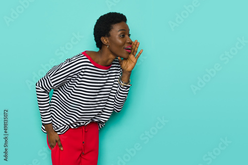 Black young woman in striped blouse is holding hand on chin and tallking. photo