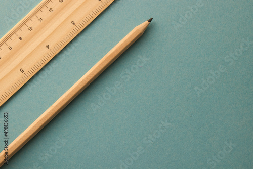 A pencil and ruler lying on the turquoise background on the left side
