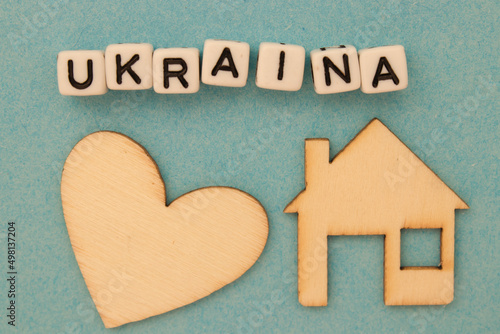 Napis Ukraina leżący nad drewnianym sercem i domem - symobliczne znaczenie