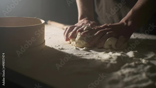 Close-up, hands of a cook in a bakery kneading dough and preparing bread according to a traditional recipe, isolated on a black background photo