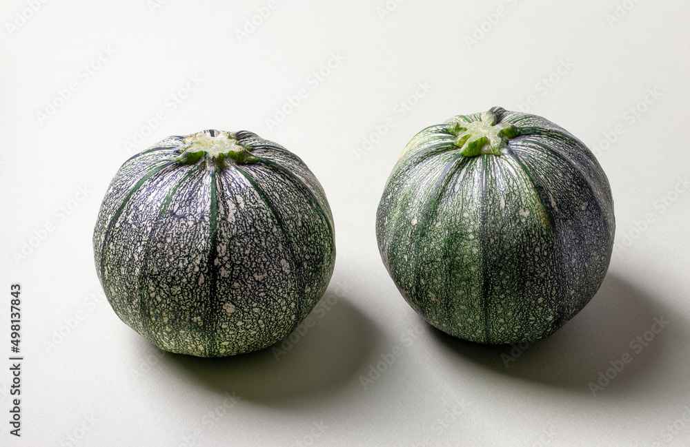 Two round green zucchini on a light background with a shadow. Closeup Two round green zucchini on a light background with a shadow. Closeup