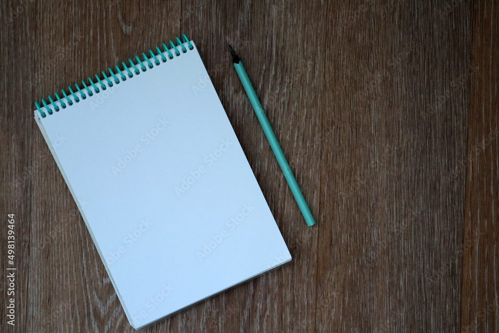 Mockup of open empty blank page of white spiral notepad with blue pencil on wooden background. Copy space for your text. Mockup of open empty blank page of white spiral notepad with blue pencil on wooden background. Copy space for your text.