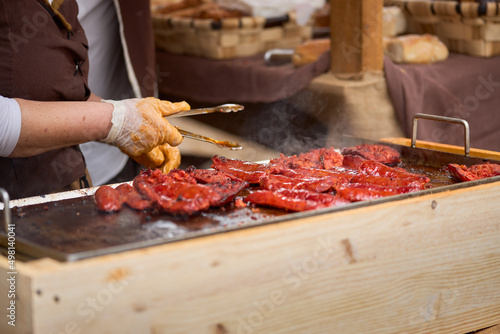 Close-up of a street stall where sausages are cooked.
