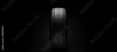 New car tire. Road wheel on dark background. Summer Tire with asymmetric tread design. Driving car concept.