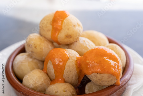 Papas arrugadas in clay plate and spicy mojo sauce on top. Traditional wrinkled potatoes snack food from Gran Canaria island, Spain photo