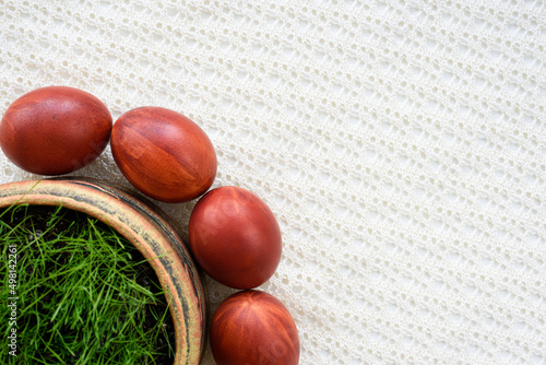 Top view of easter eggs, lying on a lace tablecloth. Painted brown. Fresh green oats grass.