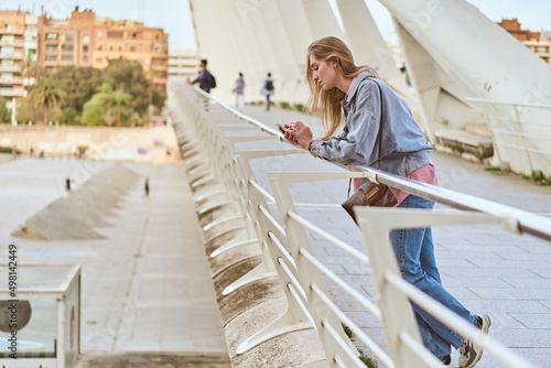 Young woman browsing smartphone on a modern bridge © Miguel Moebius