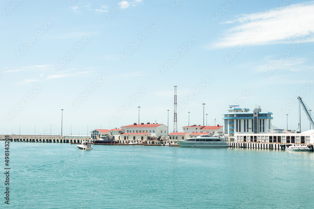 Motor ships and yachts on the pier in front of the Marine Station. Close-up. Calm Black Sea. Sea trade port with mooring boats at sunset in Sochi, Russia
