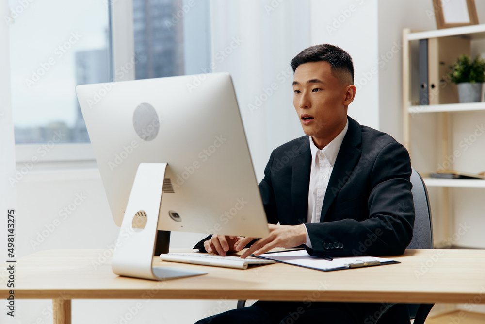man in a suit sits at a table in front of a computer Lifestyle man in a suit sits at a table in front of a computer Lifestyle