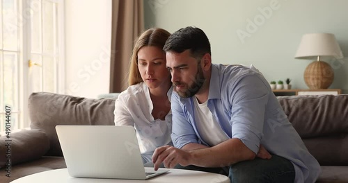 Couple sit on sofa at home use laptop read email, got commercial offer, low price, discount, online lottery, auction victory, feel happy, looks overjoyed. Moment of win, success, achievement concept photo