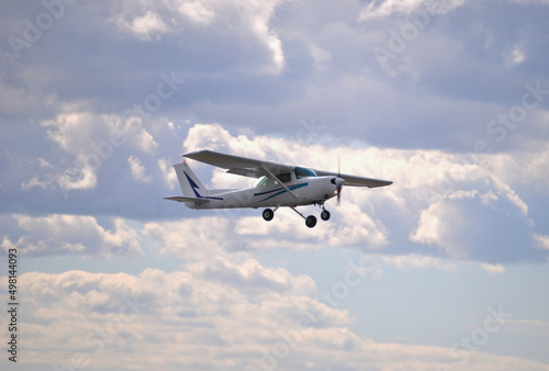 Avioneta branca com luzes acesas a voar no céu, avião pequeno, céu enublado