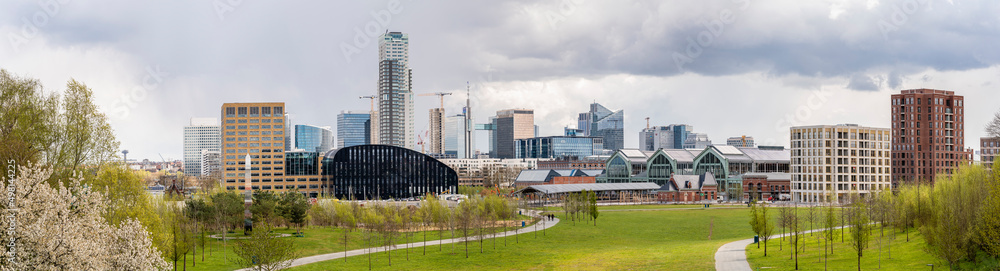 Panoramic cityscape of Brussels city center and economic district with skyscrapers in spring on a sunny day with a dramatic sky and a green park in the foreground