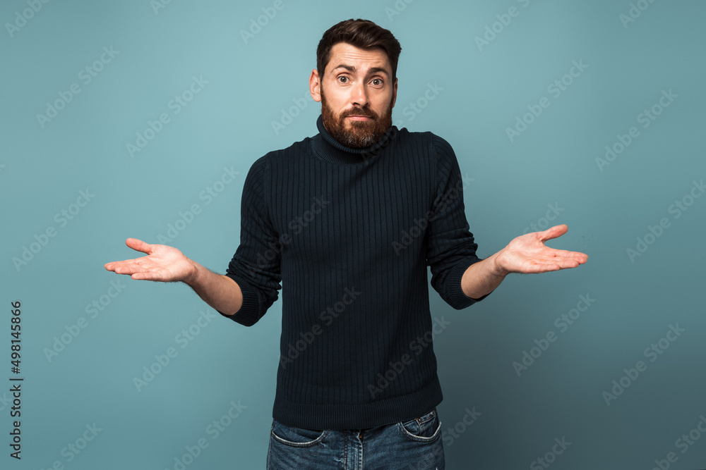 Confused handsome bearded young man in standing with raised arms Confused handsome bearded young man in standing with raised arms