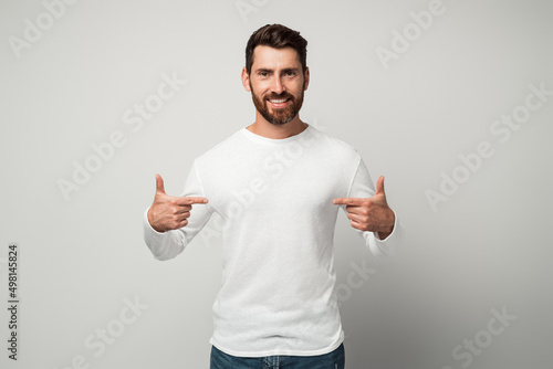 Self-confident narcissistic man smiling satisfied and pointing himself photo