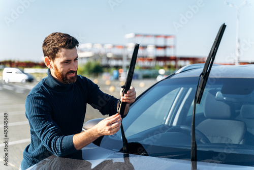 Male auto owner checking windshield wiper at the street