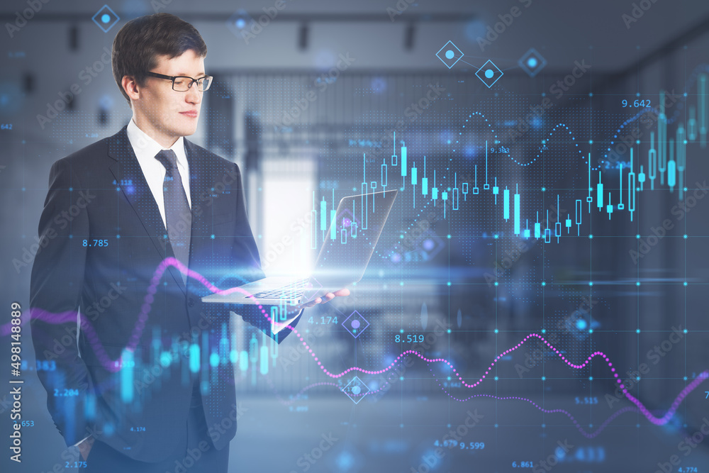 Attractive young european businessman using laptop while standing in blurry office interior with glowing forex chart hologram. Trade, finance and market concept. Double exposure. Attractive young european businessman using laptop while standing in blurry office interior with glowing forex chart hologram. Trade, finance and market concept. Double exposure.