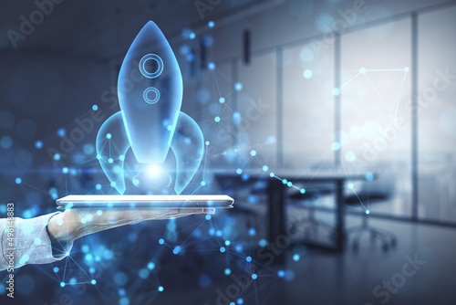 Billede på lærred Close up of female hand holding phone with abstract glowing blue rocket space ship on blurry office interior background