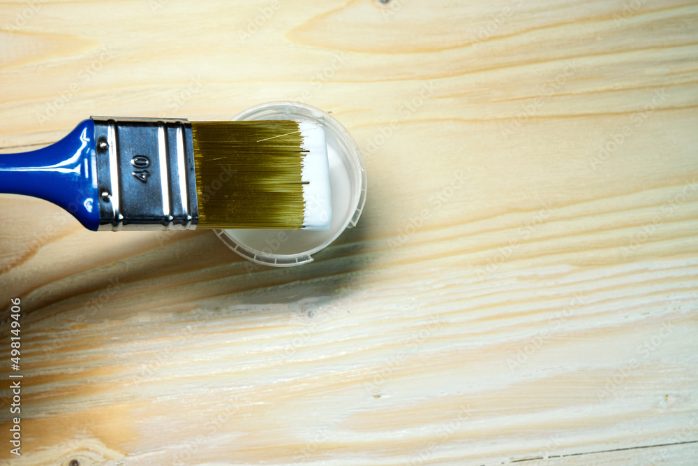 Copy space with paint brush on can lying on wooden background. Close-up paintbrush with liquid white paint on the brush. Painting tools on wooden surface. Top view. Copyspace. Vintage style. Copy space with paint brush on can lying on wooden background. Close-up paintbrush with liquid white paint on the brush. Painting tools on wooden surface. Top view. Copyspace. Vintage style.