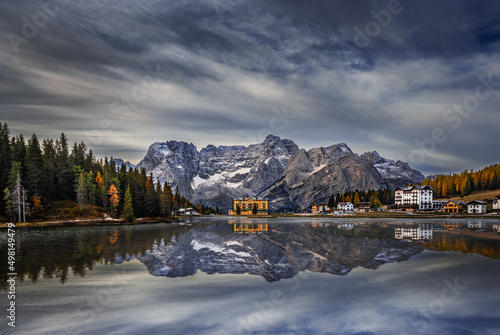 Misurina, Italy - Cristallo mountains of the Italian Dolomites reflecting in beautiful Lake Misurina in South Tyrol with morning autumn lights, cloudy sky and Istituto Pio XII rehabilitation centre photo