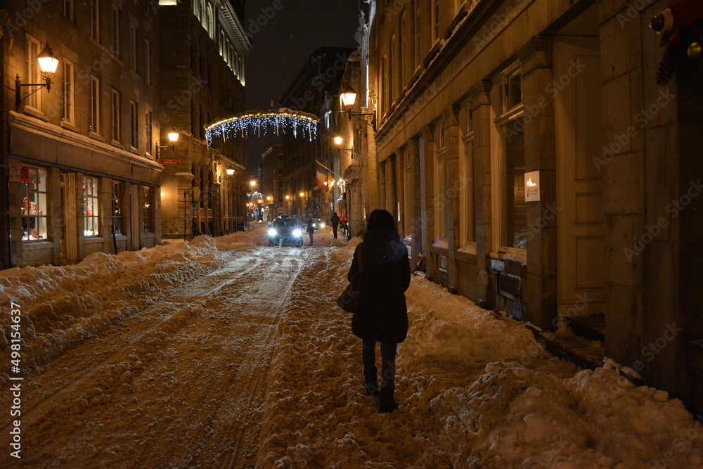 A woman walking down a street at night in Montreal