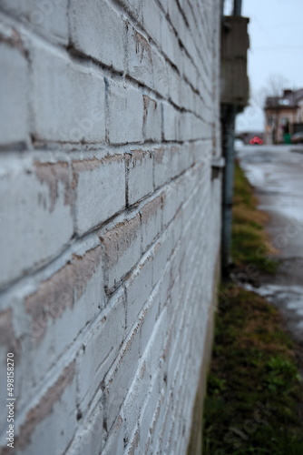 white wall, bricks painted white with paint peeling off, rainy day