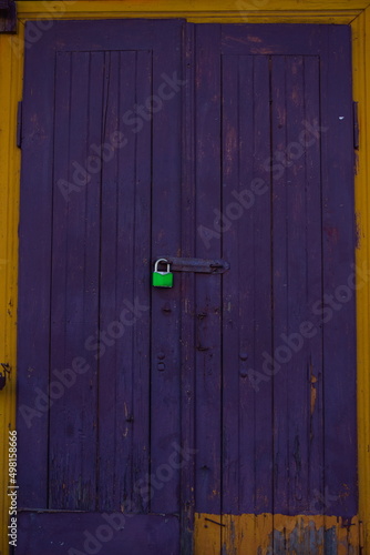 dark purple door to the old house with green padlock
