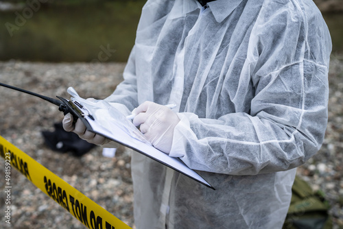 Close up on hands of unknown man crime scene detective inspector during investigation collecting evidence on the crime scene forensics write in chart photo