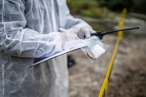 Close up on hands of unknown man crime scene detective inspector during investigation collecting evidence on the crime scene forensics write in chart photo