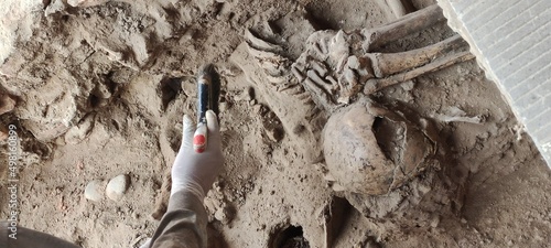 Tablou pe pânză An archaeologist using a brush in the dirt to make a discovery at an archaeologi