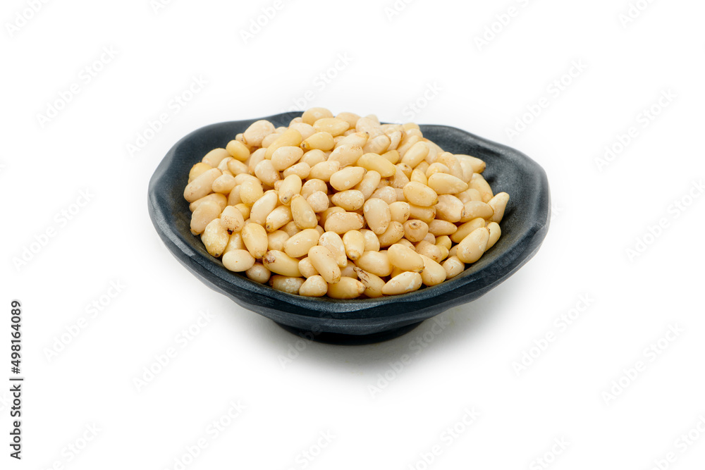 Pine Nuts in a Black Bowl Isolated on a White Background. Hulled cedar seeds Pine Nuts in a Black Bowl Isolated on a White Background. Hulled cedar seeds