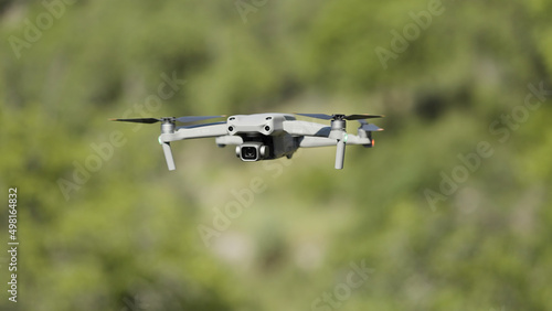 Flying drone in air. Action. Drone flies over green trees. New model of drone in air shoots green trees in summer