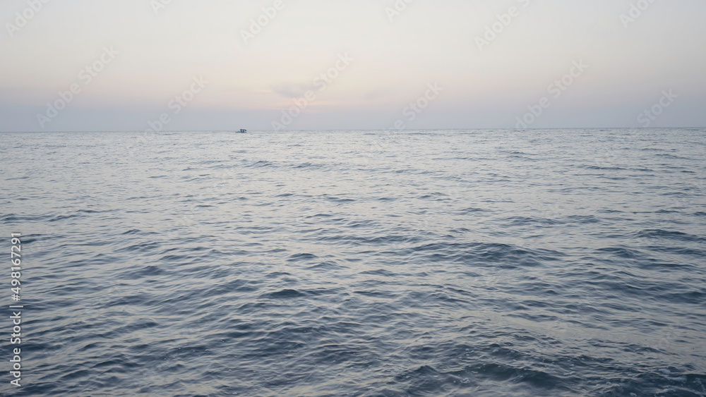 Beautiful long sea. Action. The undulating sea in the landscape against the background of a slightly misty sky, behind which ships sail in the distance.