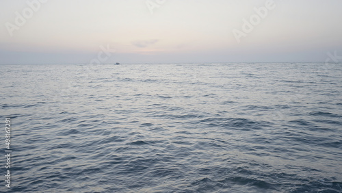 Beautiful long sea. Action. The undulating sea in the landscape against the background of a slightly misty sky, behind which ships sail in the distance.